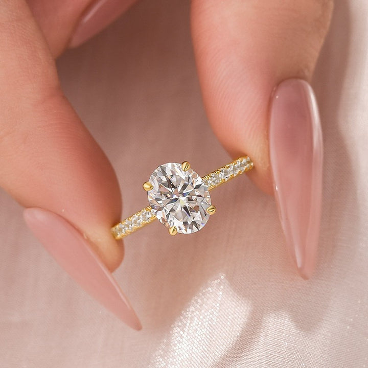 Close-up of an oval pavé moissanite ring held by hand