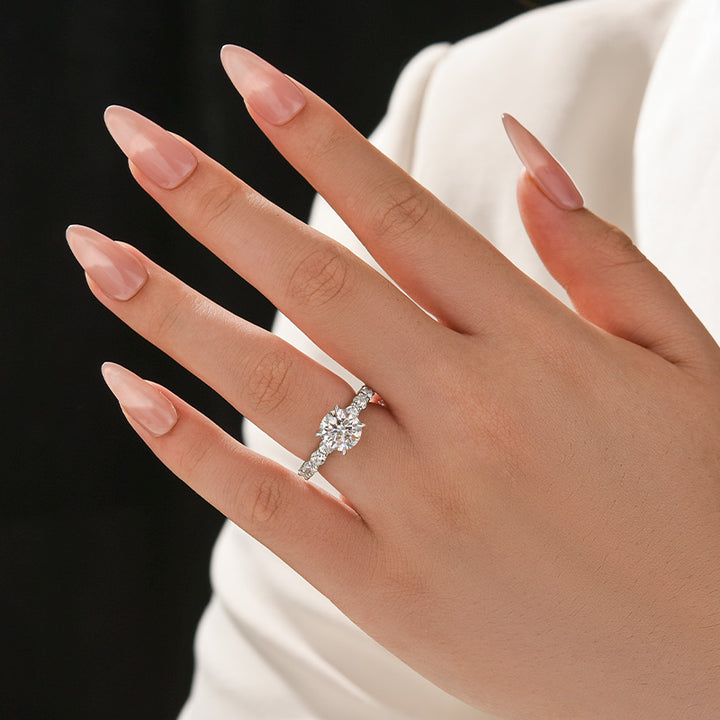 Four-prong round moissanite ring styled on hand with a black and white background