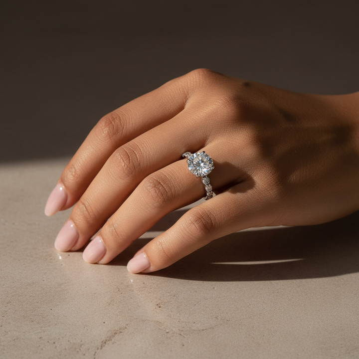 Round moissanite engagement ring worn on hand in warm indoor light